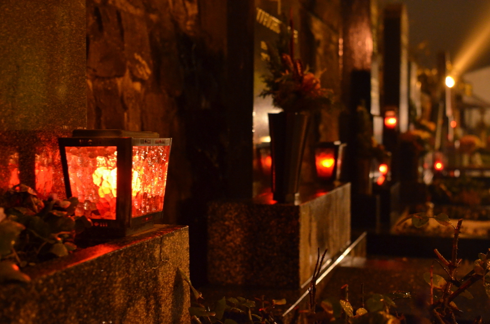 Friedhof mit angezündeten Laternen in der Dunkelheit. 